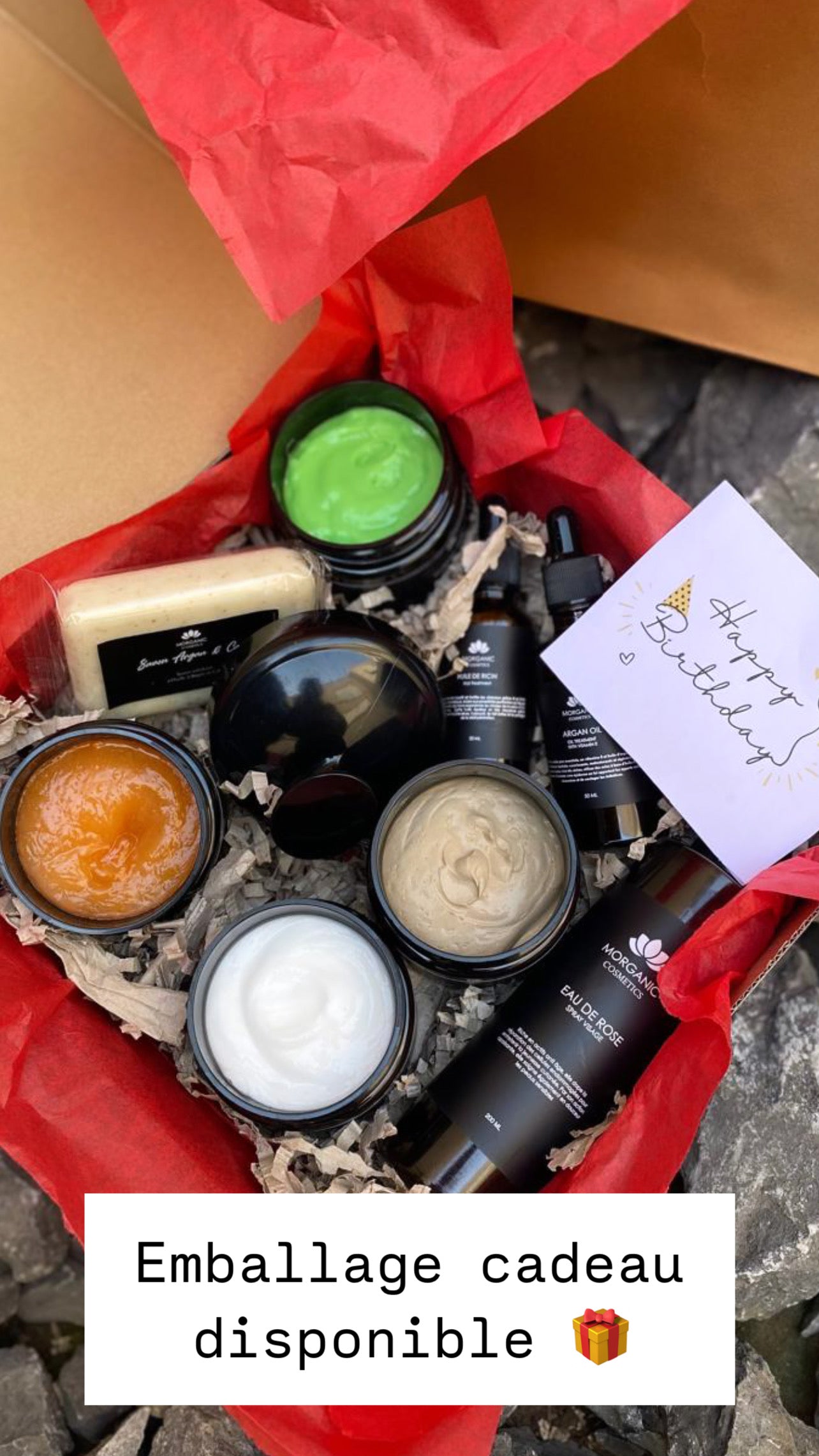 Coffret cadeau contenant des produits de soin bio marocains, décoré avec papier rouge et un message d'anniversaire.